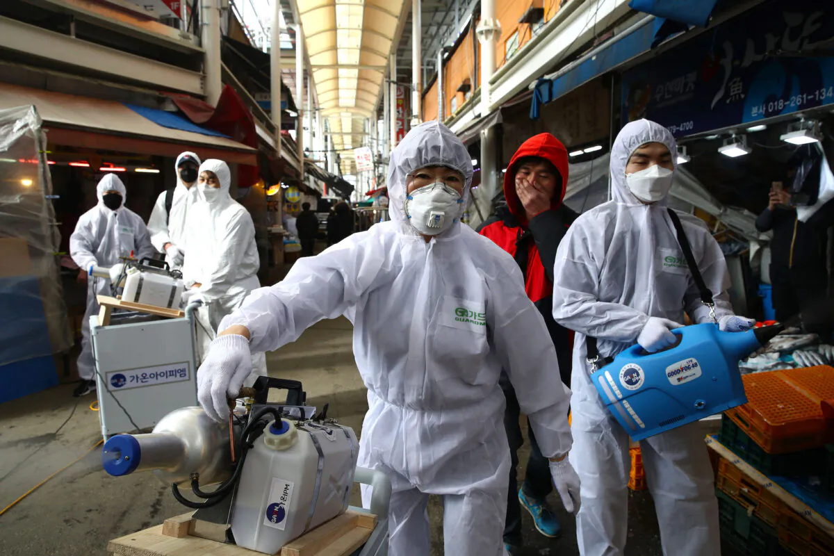 Disinfection professionals wearing protective gear spray anti-septic solution against the coronavirus at a traditional market in Seoul on Feb. 26, 2020. (Chung Sung-Jun/Getty Images)