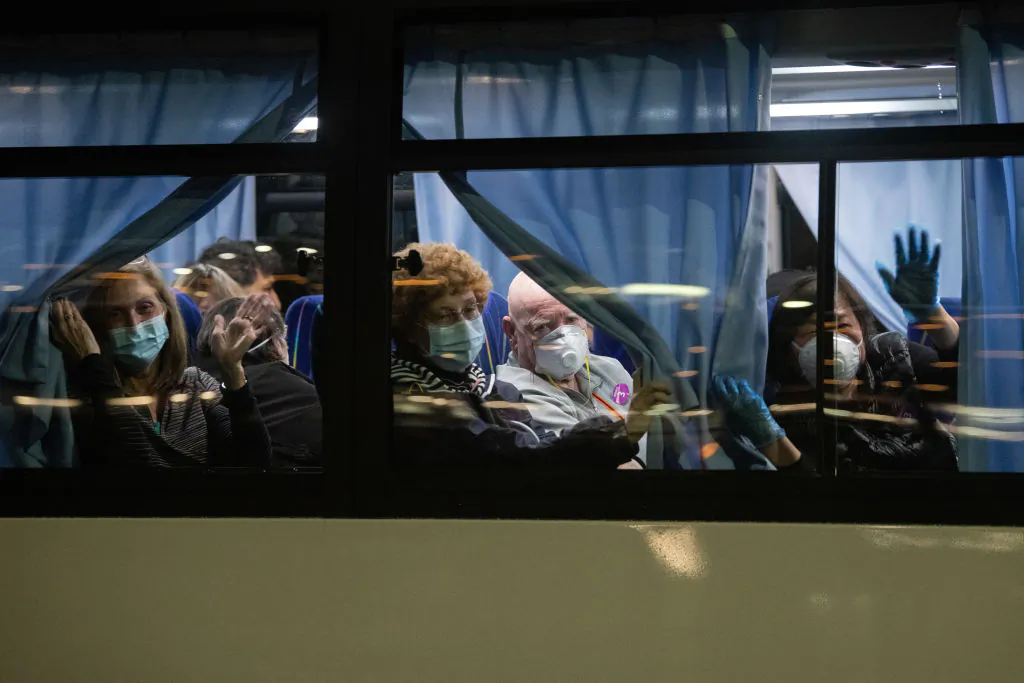 American citizens wave from a bus as they leave the quarantined Diamond Princess cruise ship at Daikoku Pier to be repatriated to the United States on Feb. 17, 2020, in Yokohama, Japan. Some passengers who have tested positive for coronavirus may be transferred to a facility in Costa Mesa, Calif. (Carl Court/Getty Images)