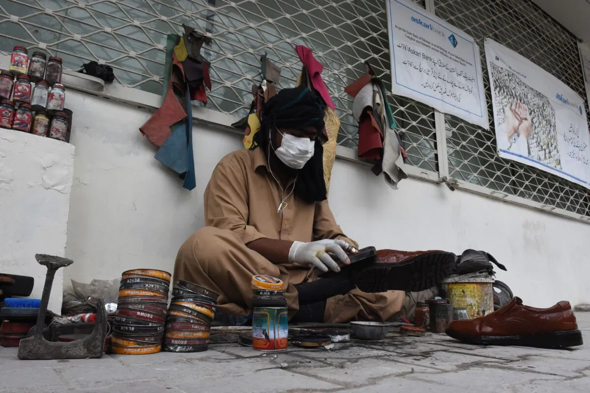 A cobbler wears a protective facemask as a prevention measure against COVID-19 coronavirus as he polishes shoes in a street in Quetta, Pakistan, on Feb. 27, 2020. (Banaras Khan /AFP via Getty Images)