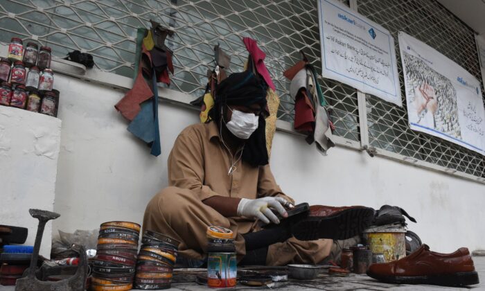 A cobbler wears a protective facemask as a prevention measure against COVID-19 coronavirus as he polishes shoes in a street in Quetta, Pakistan, on Feb. 27, 2020. (Banaras Khan /AFP via Getty Images)