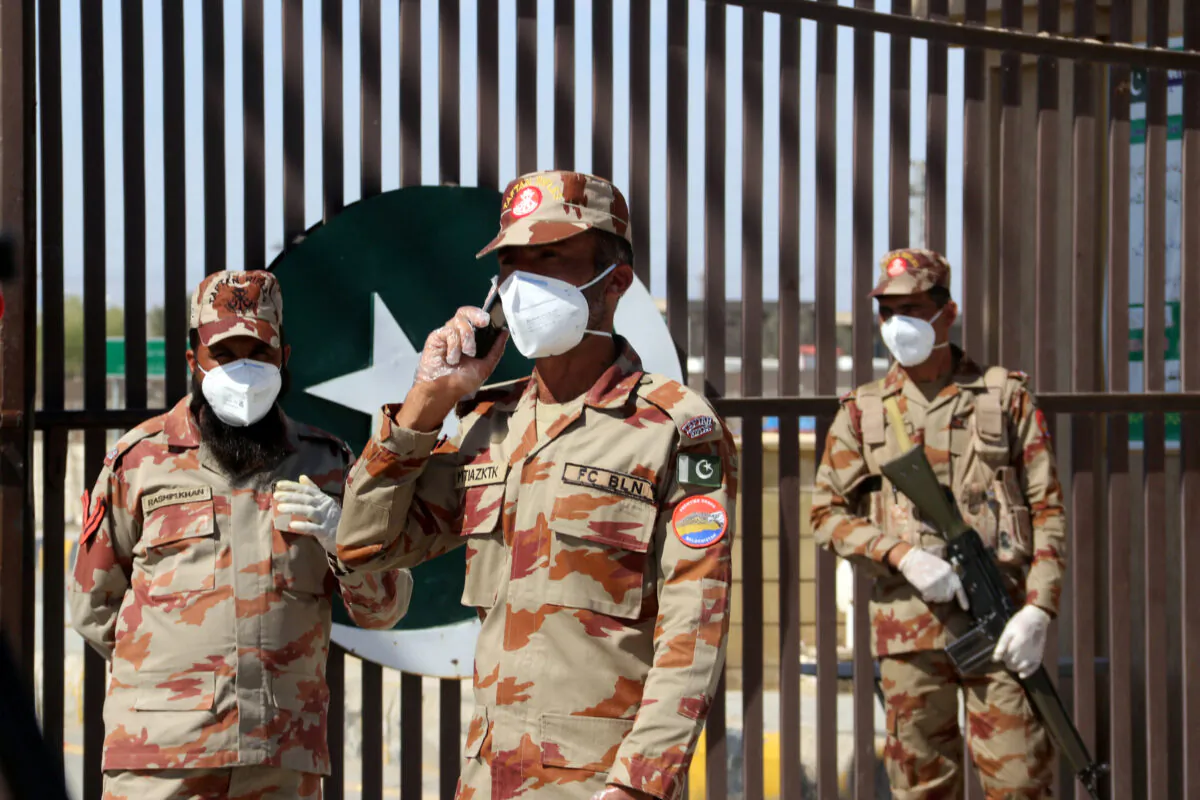 Paramilitary soldiers in front of a closed gate of Pakistan's border post, after Pakistan sealed its border with Iran as a preventive measure following the coronavirus outbreak, at the border post in Taftan, Pakistan, on Feb. 25, 2020. (Naseer Ahmed/Reuters)