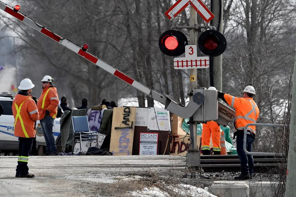 CN Railway workers check the railroad crossing gate as they prepare to resume service after Ontario Provincial Police made arrests at a rail blockade in Tyendinaga Mohawk Territory, near Belleville, Ont., on Feb. 24, 2020, during a protest in solidarity with Wet'suwet'en Nation hereditary chiefs attempting to halt construction of a natural gas pipeline on their traditional territories. (Adrian Wyld/The Canadian Press)