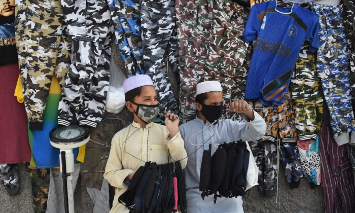 Facemask vendors wear protective facemasks as a prevention measure against the COVID-19 coronavirus alongside a street in Quetta, Pakistan on Feb. 27, 2020. (Banaras Khan/AFP via Getty Images)