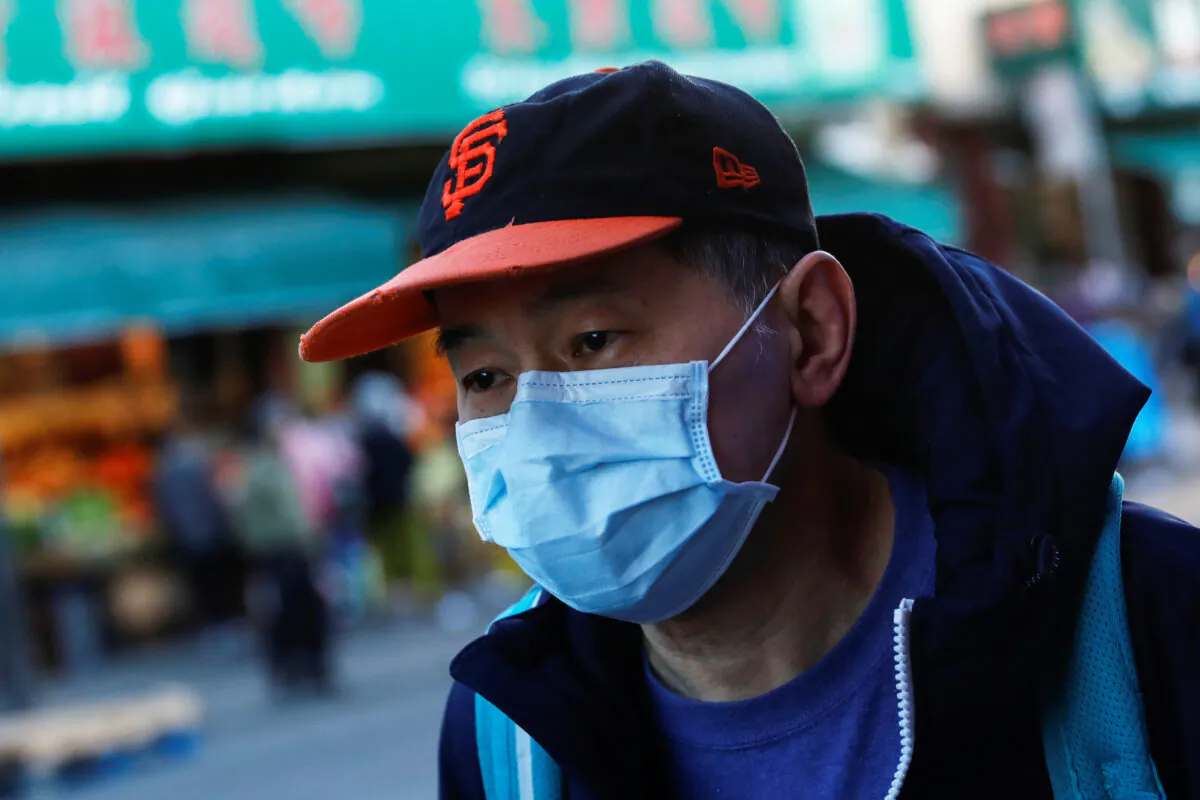 A man wears a face mask while waiting for a public bus in the Chinatown section of San Francisco, California, on Feb. 25, 2020. (Shannon Stapleton/Reuters)