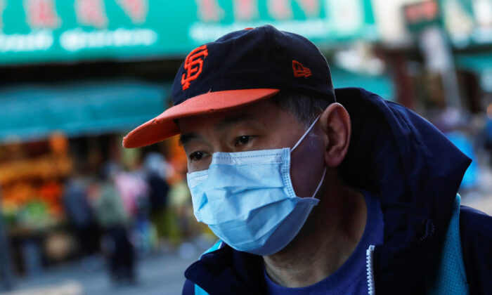 A man wears a face mask while waiting for a public bus in the Chinatown section of San Francisco, California, on Feb. 25, 2020. (Shannon Stapleton/Reuters)