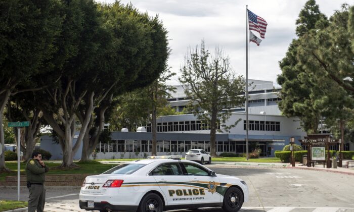 In this Feb. 22, 2020, file photo, a police officer stands guard by the Fairview Development Center in Costa Mesa, Calif., after if was announced that the center may be used to house coronavirus patients. (Mindy Schauer/The Orange County Register via AP) 