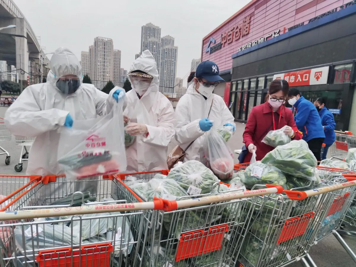 Community workers and volunteers wearing face masks sort and pack groceries from a supermarket purchased through group orders after supermarkets stopped selling to individuals, in Wuhan, the epicenter of the novel coronavirus outbreak, in Hubei Province, China on Feb. 24, 2020. (China Daily via Reuters)