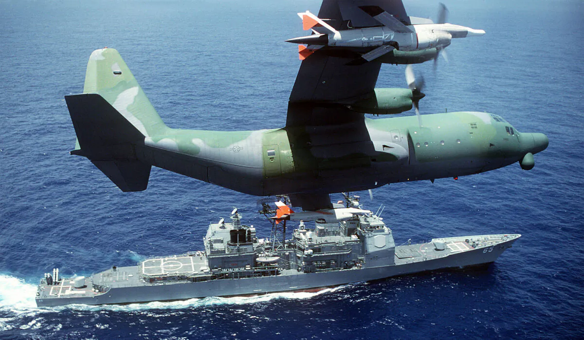 A DC-130H Hercules drone control aircraft banks to the left while passing over the guided missile cruiser USS CHOSIN (CG-65). (Photo by USAF)