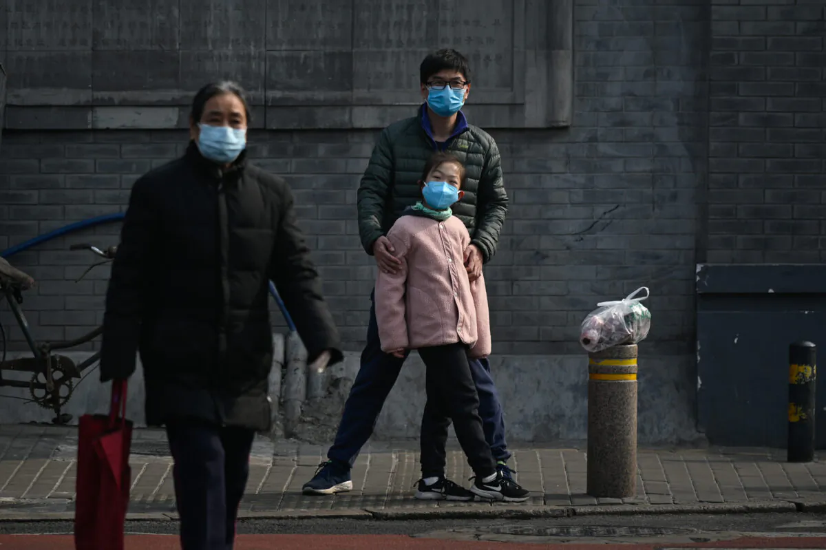 A man and a girl wearing face masks wait to cross a street in Beijing, China on Feb. 28, 2020. (STR/AFP via Getty Images)
