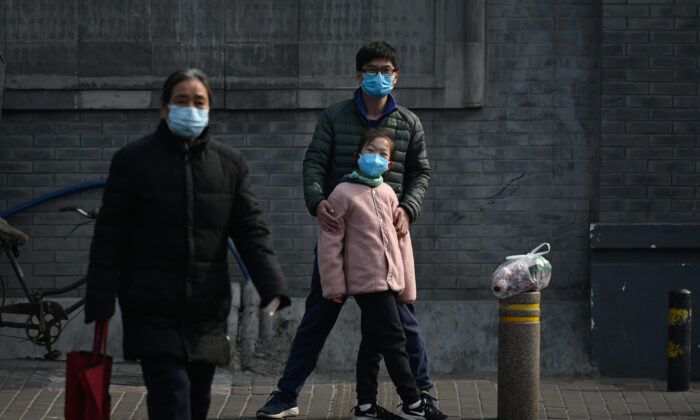 A man and a girl wearing face masks wait to cross a street in Beijing, China on Feb. 28, 2020. (STR/AFP via Getty Images)