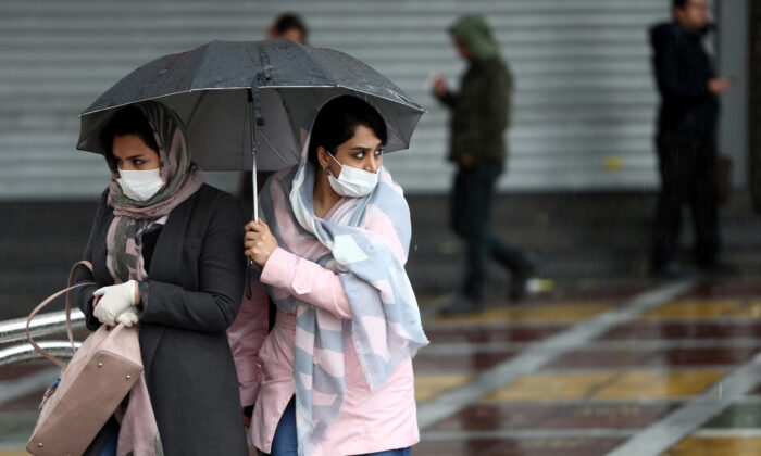 Iranian women wear protective masks to prevent spreading the coronavirus, as they walk in the street in Tehran, Iran on Feb. 25, 2020. (Nazanin Tabatabaee/West Asia News Agency via Reuters)