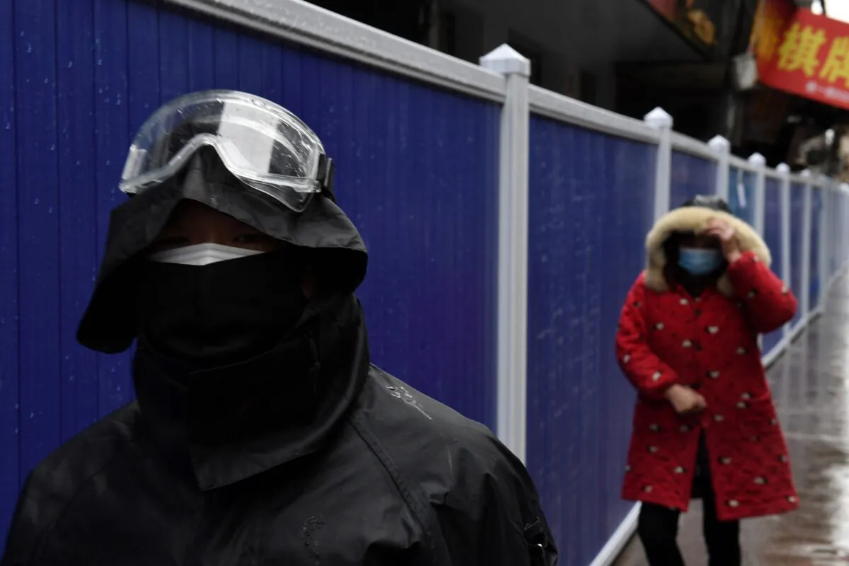 People wearing face masks walk next to barriers set up at a residential area in Wuhan, the epicenter of the novel coronavirus outbreak, Hubei Province, China, on Feb. 28, 2020. (Stringer/Reuters)