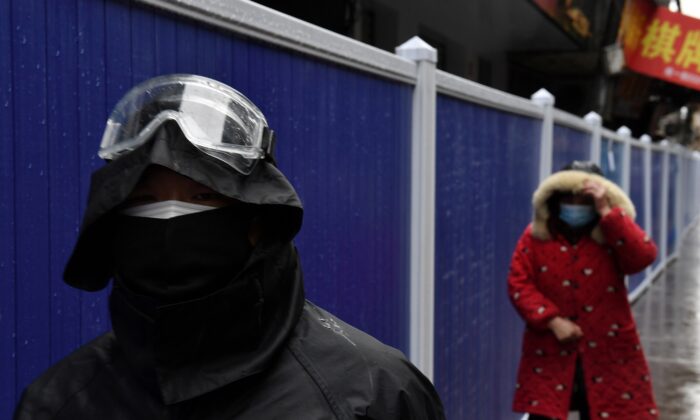 People wearing face masks walk next to barriers set up at a residential area in Wuhan, the epicenter of the novel coronavirus outbreak, Hubei Province, China, on Feb. 28, 2020. (Stringer/Reuters)