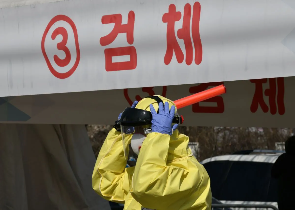 A medical member wearing protective gear guides drivers with suspected symptoms of the COVID-19 coronavirus, at a "drive-through" virus test facility in Goyang, north of Seoul, on Feb. 29, 2020. (Jung Yeonje-JE/AFP via Getty Images)