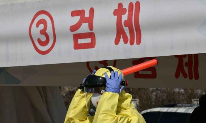 A medical member wearing protective gear guides drivers with suspected symptoms of the COVID-19 coronavirus, at a "drive-through" virus test facility in Goyang, north of Seoul, on Feb. 29, 2020. (Jung Yeonje-JE/AFP via Getty Images)