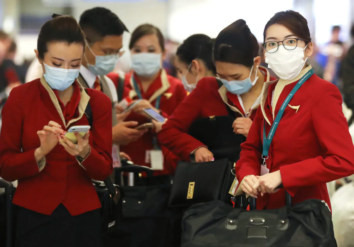 A flight crew from Cathay Pacific Airways wearing protective masks stand in the international terminal after arriving on a flight from Hong Kong at Los Angeles International Airport in Los Angeles, California, on Feb. 28, 2020. (Mario Tama/Getty Images)