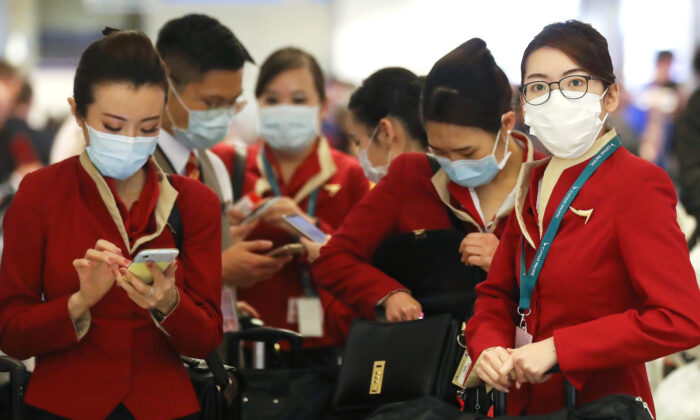 A flight crew from Cathay Pacific Airways wearing protective masks stand in the international terminal after arriving on a flight from Hong Kong at Los Angeles International Airport in Los Angeles, California, on Feb. 28, 2020. (Mario Tama/Getty Images)