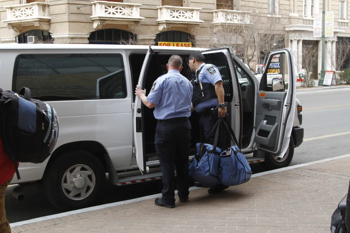 Immigration guards finish loading a van of immigrants leaving court under guard on Feb. 28, 2020, in El Paso, Texas. (AP Photo/Cedar Attanasio)
