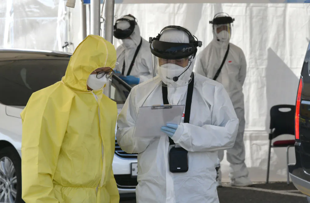 Medical members wearing protective gear talk as they check drivers with suspected symptoms of the novel coronavirus, at a "drive-through" virus test facility in Goyang, South Korea, on Feb. 29, 2020. (Jung Yeon-je/AFP via Getty Images)