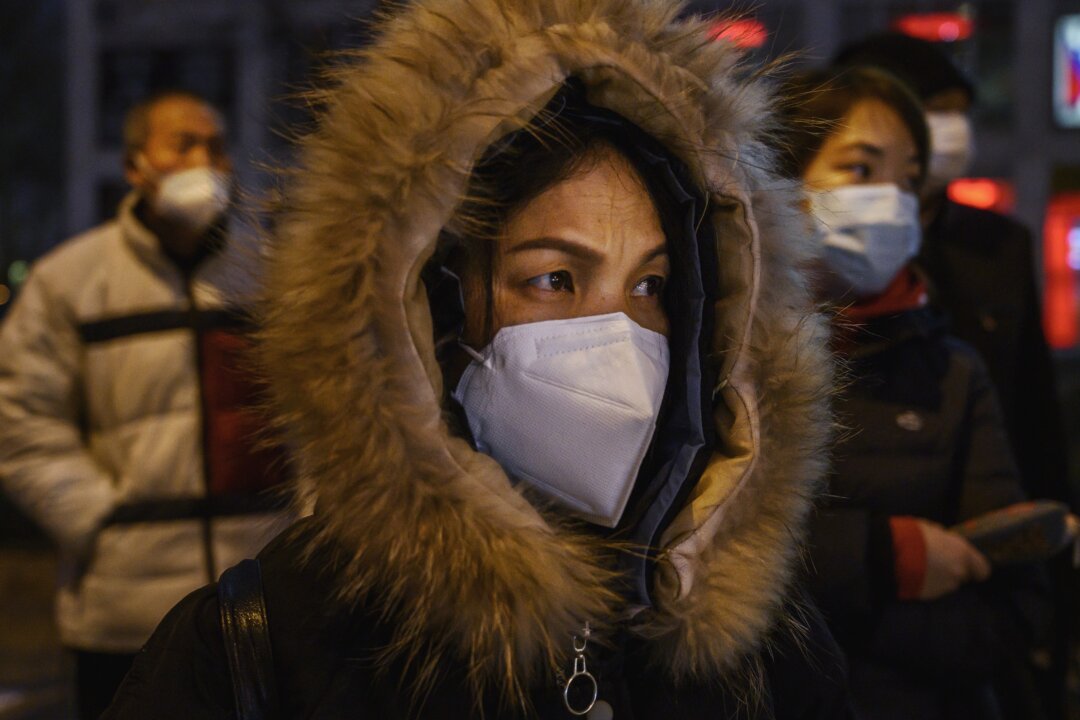 Chinese office workers wear protective masks as they line up for the bus after work in Beijing on March 2, 2020. (Kevin Frayer/Getty Images)