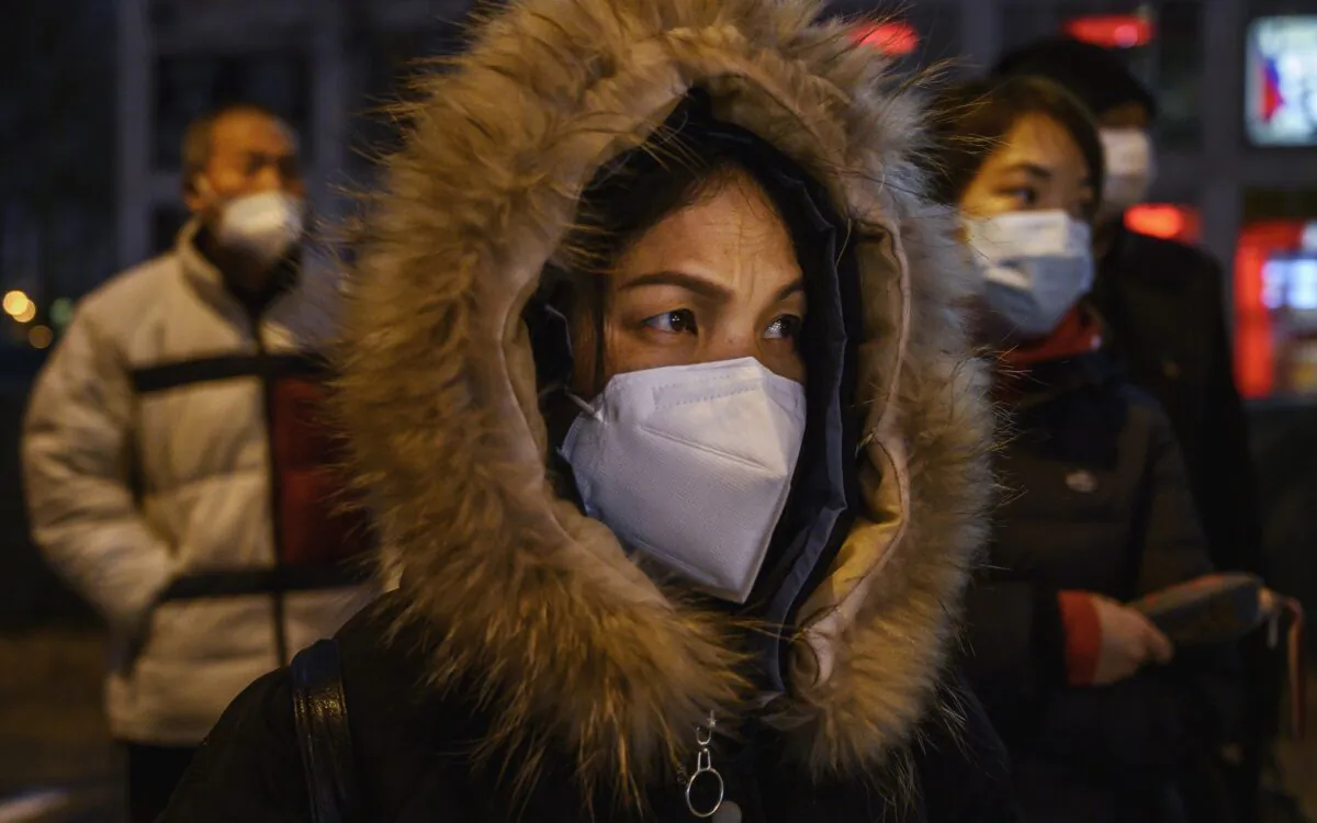 Chinese office workers wear protective masks as they line up for the bus after work in Beijing on March 2, 2020. (Kevin Frayer/Getty Images)