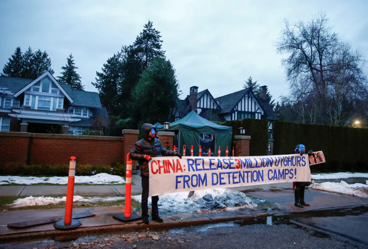 Protesters hold a large sign against China's Uyghur camps, labeled as vocational training centers by the Chinese regime, outside the home of Huawei Chief Financial Officer Meng Wanzhou before her extradition hearing at B.C. Supreme Court in Vancouver, British Columbia, Canada, on Jan. 20, 2020. (Lindsey Wasson/Reuters)