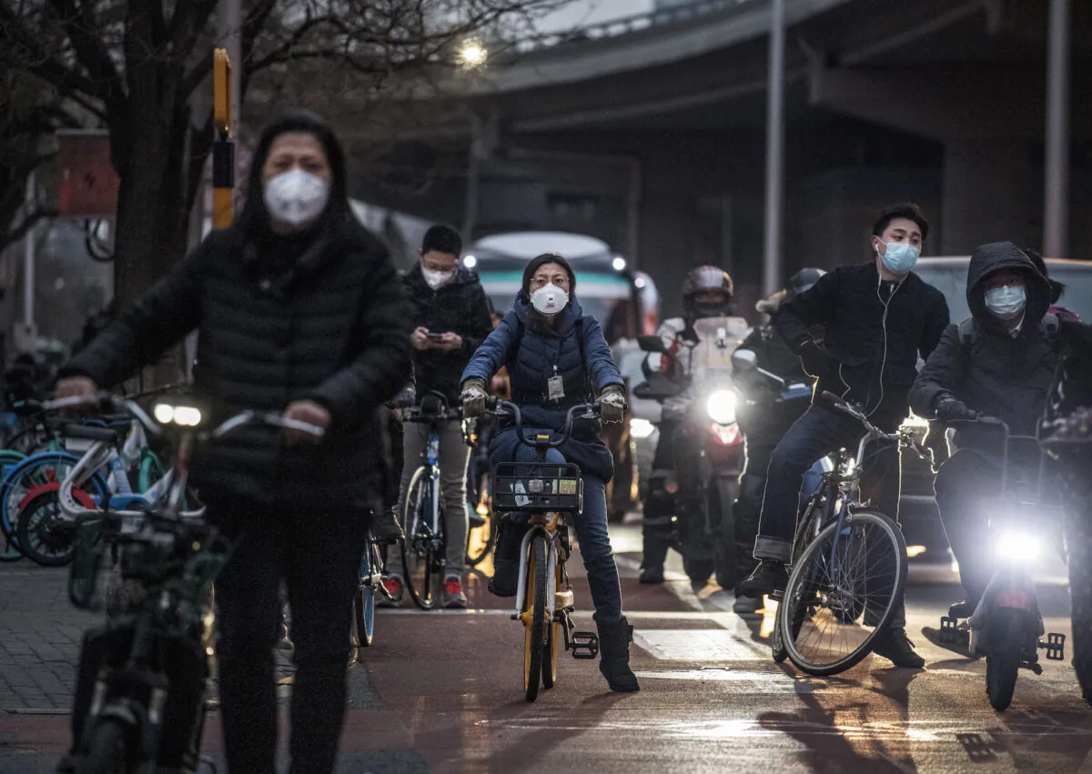 Chinese commuters on bikes wear protective masks while waiting for a light to change after leaving work on March 2, 2020 in Beijing, China. (Kevin Frayer/Getty Images)