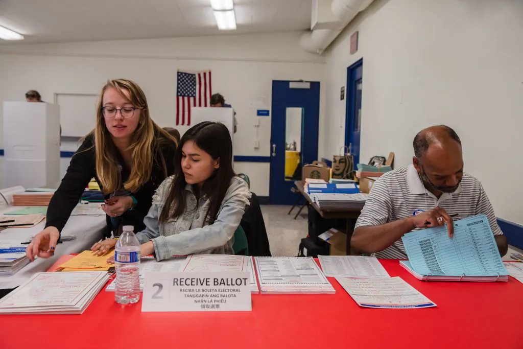 Volunteers Julian Shelby (R), Brittney Duran (C), and Natalie King assist voters at the Golden Hill Recreation Center, a polling place for the primary in San Diego on March 3, 2020. (Ariana Drehsler/AFP via Getty Images)