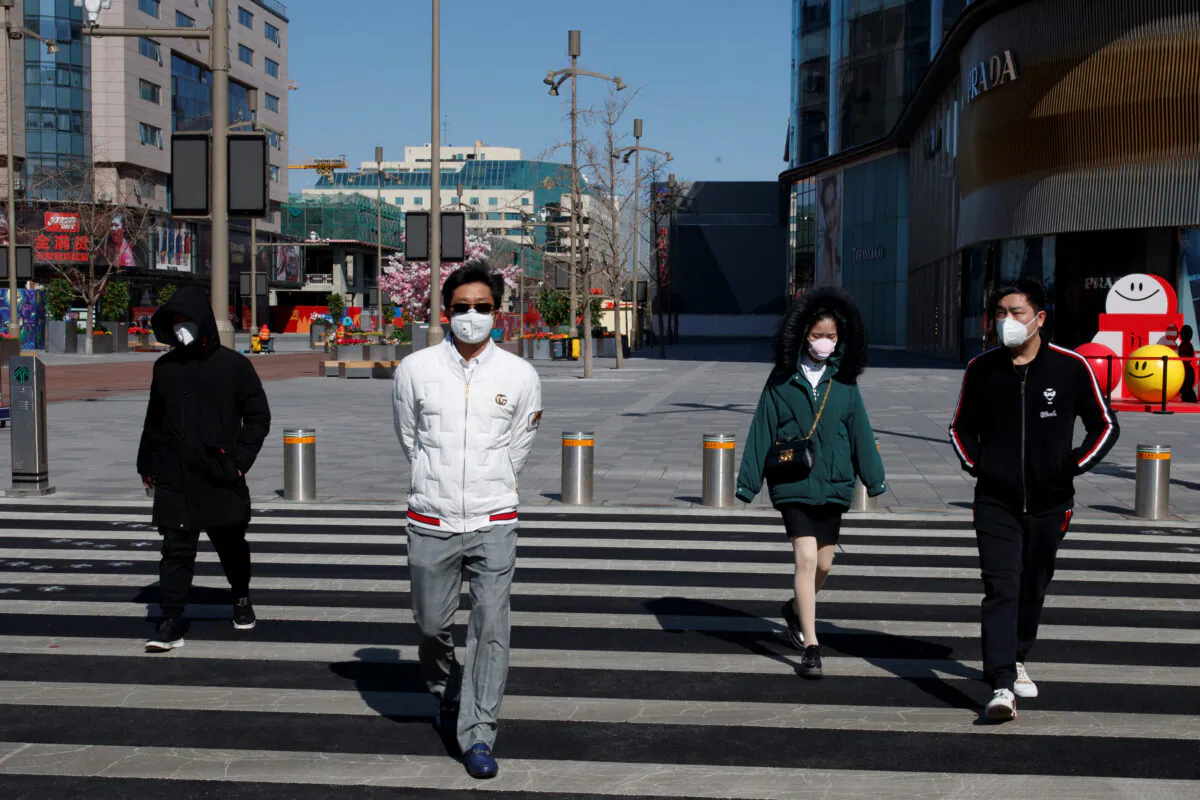 People wearing masks walk in a shopping street in Beijing, as the country is hit by an outbreak of the novel coronavirus, China, on March 3, 2020. (Thomas Peter/Reuters)