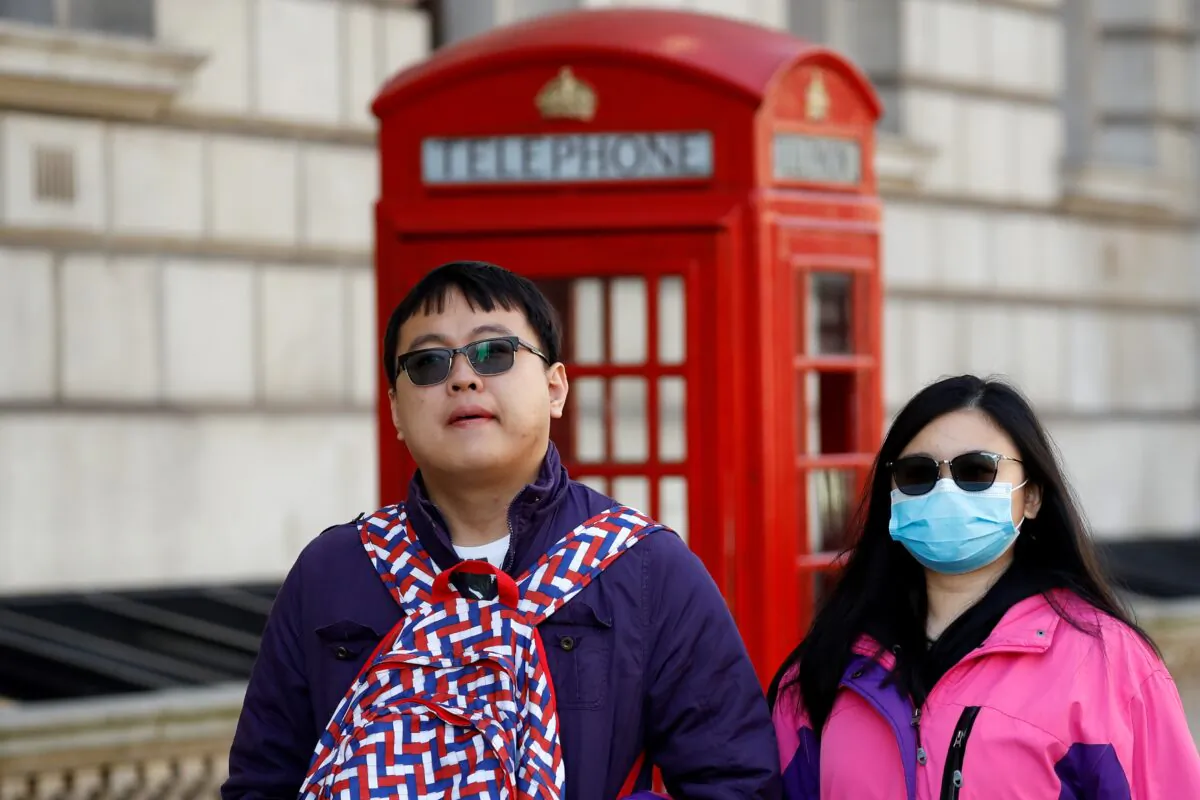 A tourist wears a surgical face mask as she walks past a red telephone box in central London on March 2, 2020. (Tolga Akmen/AFP via Getty Images)
