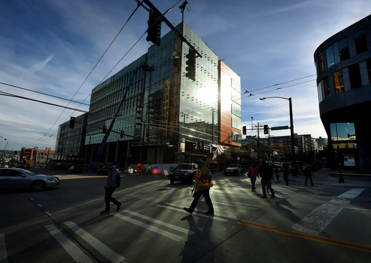 People walk past part of the new Amazon headquarter complex under construction in downtown Seattle, Washington, on Sept. 24, 2015. (Mark Ralston/AFP via Getty Images)