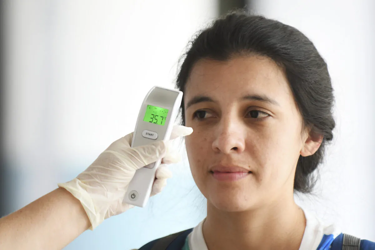 A nurse checks a passenger's body temperature as a preventive measure against the new coronavirus, COVID-19, at the Aurora International Airport, in Guatemala City, on March 4, 2020. (Johan Ordonez/AFP via Getty Images)