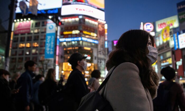 Following the outbreak of the coronavirus in Japan, a woman wearing a protective mask is seen at the scramble crossing in Shibuya shopping district in Tokyo on March 3, 2020. (Athit Perawongmetha/Reuters)