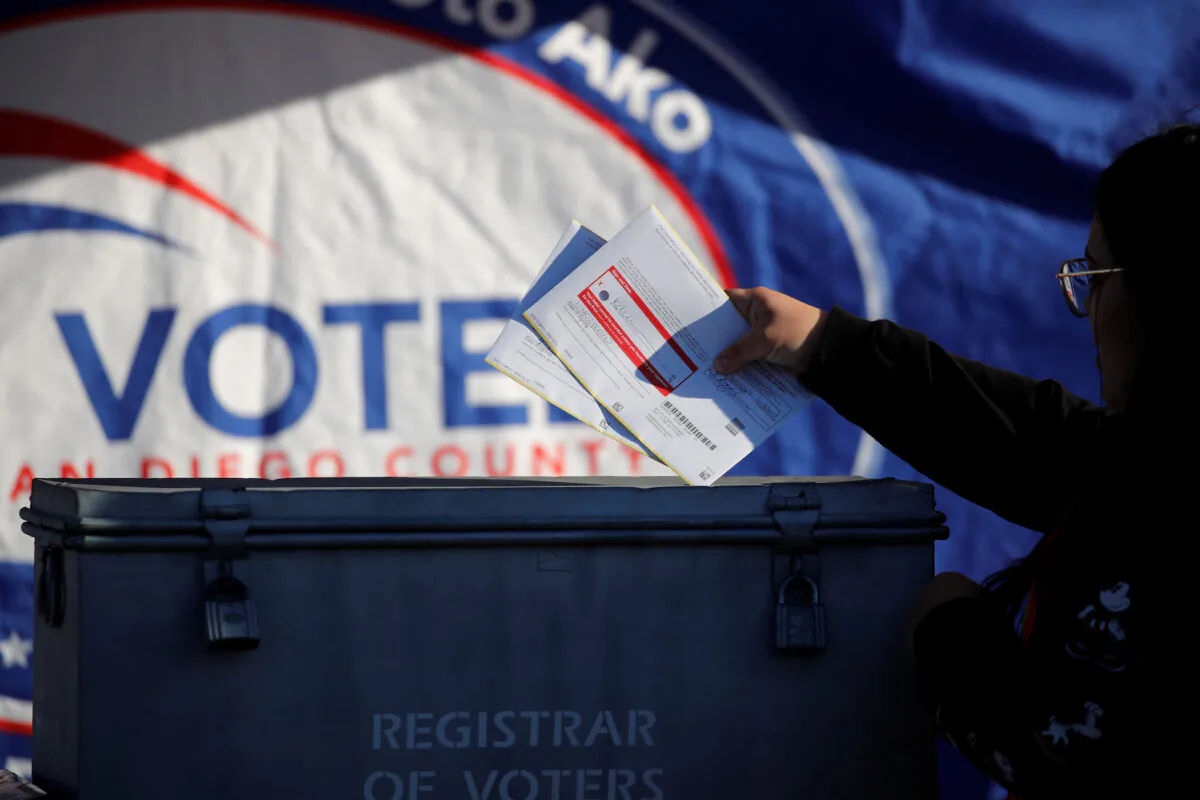 A poll worker drops ballots into a ballot box during the California primary in San Diego, Calif., on March 3, 2020. (Mike Blake/Reuters)