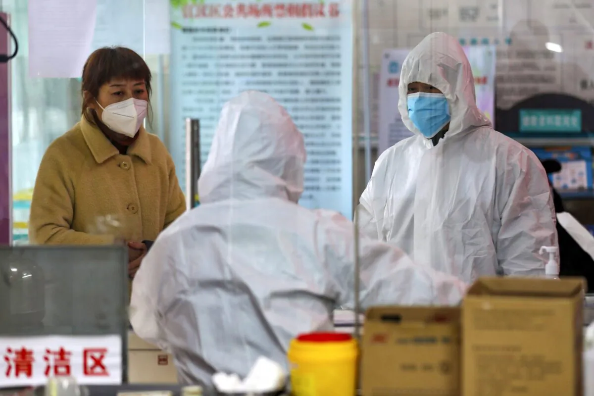 Medical workers in protective gear talk with a woman suspected of being ill with coronavirus at a community health station in Wuhan in central China's Hubei Province on Jan. 27, 2020. (Chinatopix via AP)