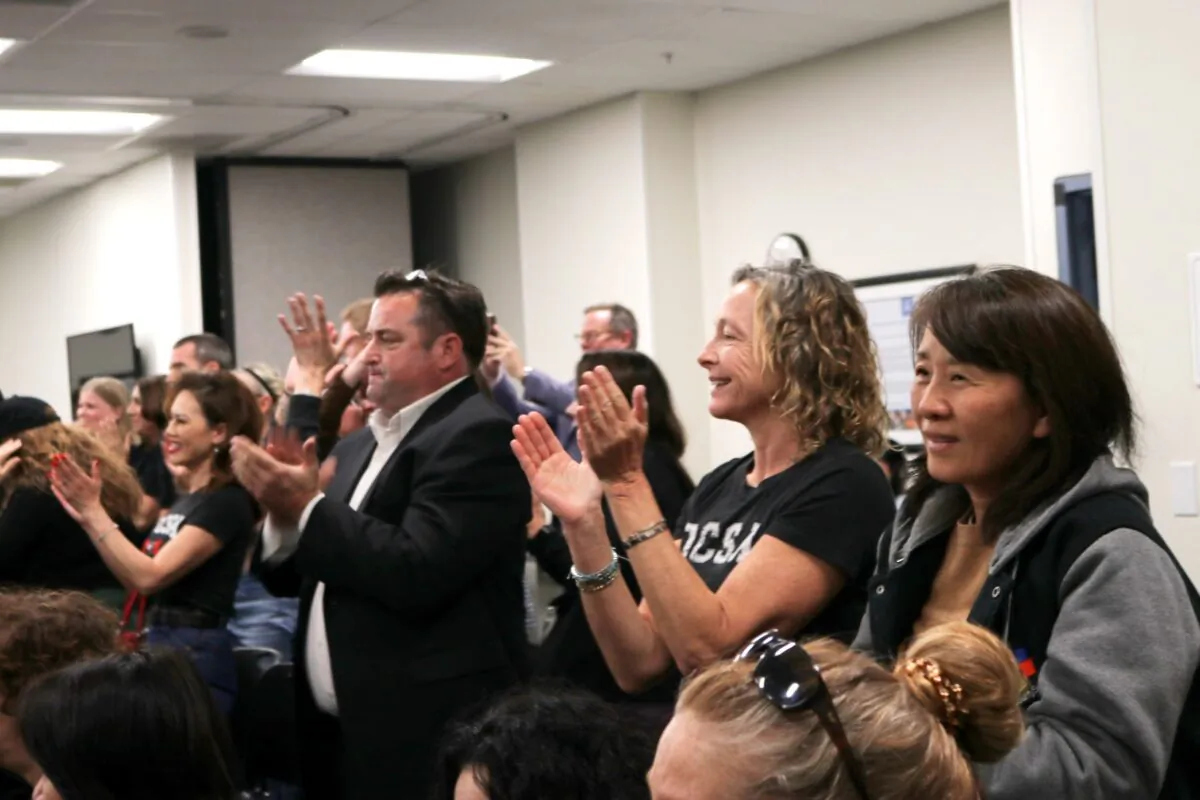 Attendees at the Orange County Board of Education meeting applaud the board’s decision to renew the license of Orange County School of the Arts and take over as the school’s authorizer, in Costa Mesa, Calif., on March 4, 2020. (Jamie Joseph/The Epoch Times)