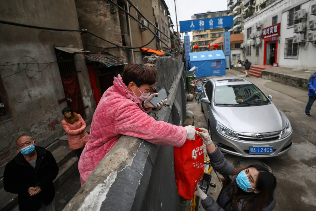 A resident (center L) receives a bag of food over a wall in Wuhan in China's central Hubei province on March 3, 2020. (STR/AFP via Getty Images)
