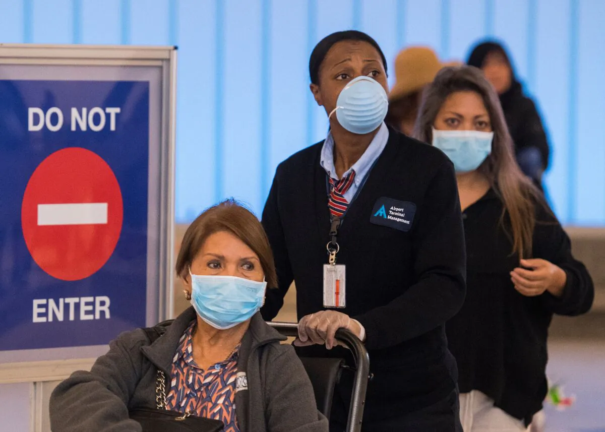 Passengers wear face masks to protect against the COVID-19 (Coronavirus) after arriving at the LAX airport in Los Angeles on March 5, 2020. (MARK RALSTON/AFP via Getty Images)