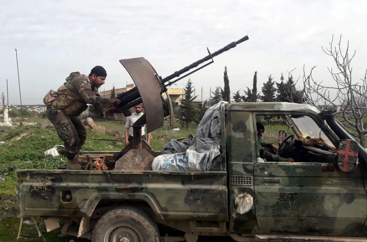 Syrian army soldiers gesture from a military vehicle in southern Idlib province, Syria, on March 5, 2020. (SANA/File/Handout via Reuters)