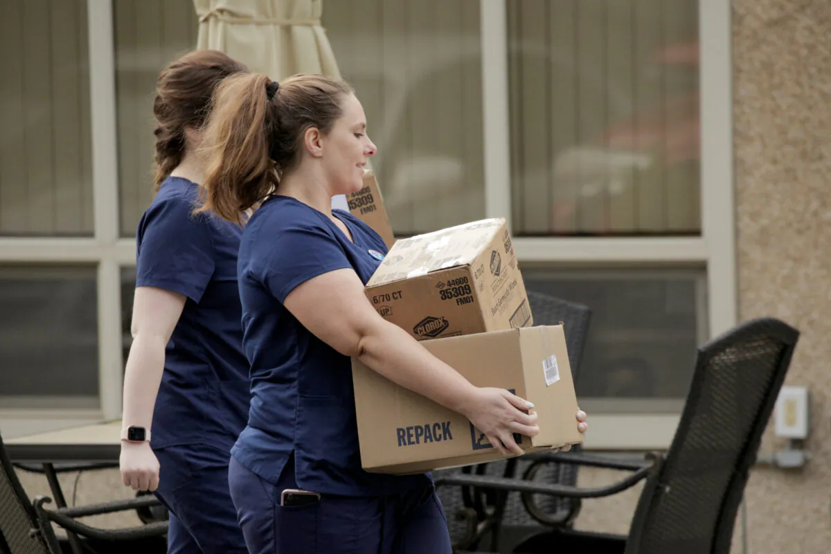Healthcare workers carry Clorox wipes and other supplies into the Life Care Center of Kirkland, the long-term care facility linked to several confirmed coronavirus cases in the state, in Kirkland, Washington on March 5, 2020. (David Ryder/Reuters)