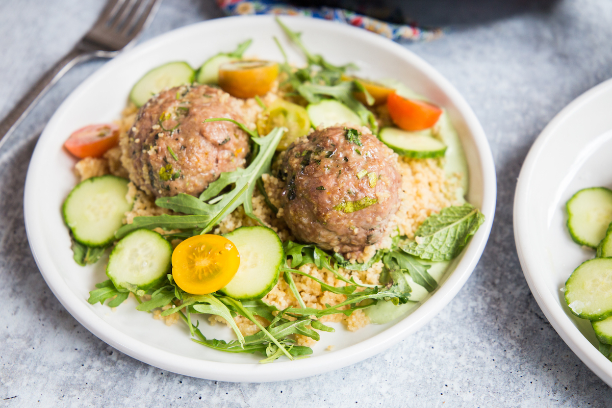 plate of lamb meatballs with couscous and vegetables closeup