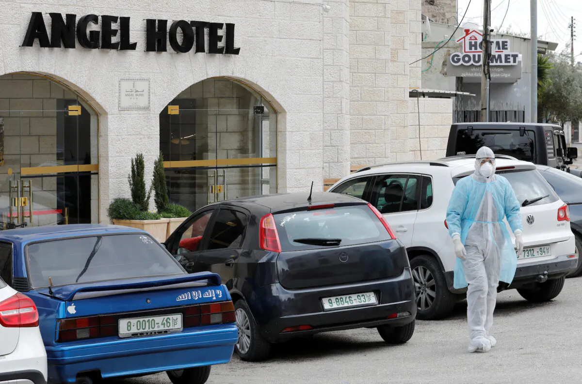 A man in a protective suit walks outside Angel Hotel where, according to a Palestinian government official, a group of American visitors have been quarantined as part of precautions against the coronavirus, in Beit Jala town in the Israeli-occupied West Bank March 7, 2020. REUTERS/Mussa Qawasma