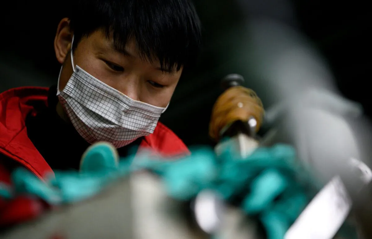 A worker wearing a face mask makes insoles at the Zhejiang Xuda Shoes Co. factory in Wenzhou, China, on Feb. 27, 2020. (Noel Celis/AFP via Getty Images)