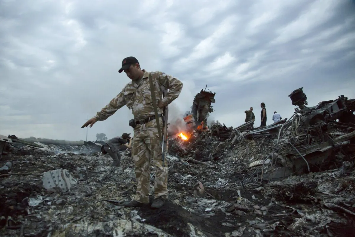 People walk amongst the debris at the crash site of MH17 passenger plane near the village of Grabovo, Ukraine, on July 17, 2014. (Dmitry Lovetsky/File via AP)