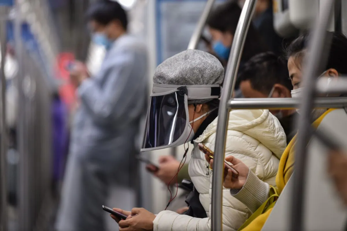 A woman wearing a plastic face cover and a mask travels on a subway train Shanghai, China on March 5, 2020. (HECTOR RETAMAL/AFP via Getty Images)