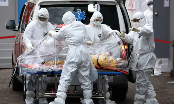 Medical staff, wearing protective gears, move a patient infected with the novel coronavirus from an ambulance to a hospital in Seoul, South Korea, on March 9, 2020. (Chung Sung-Jun/Getty Images)