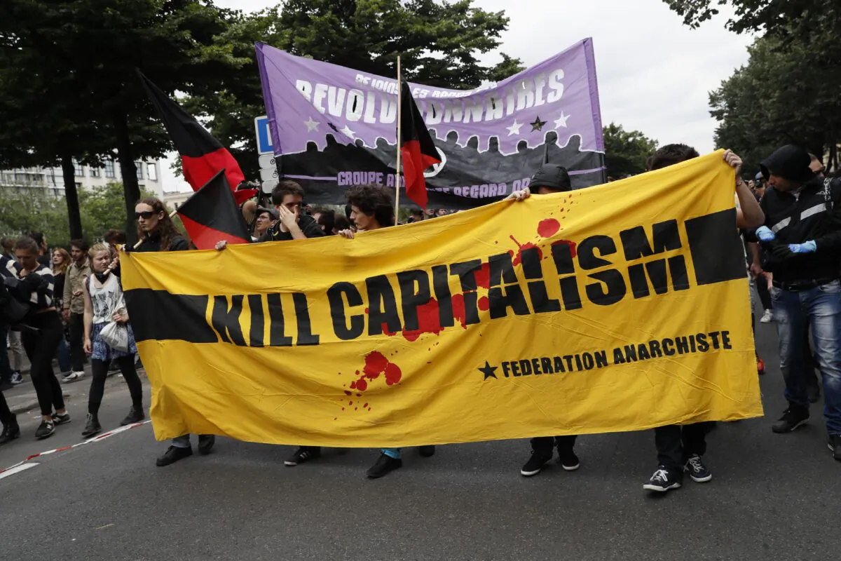 People hold a banner reading "Kill capitalism" during a demonstration against the series of controversial labour reforms in Paris on June 28, 2016. (Thomas Samson/AFP via Getty Images)