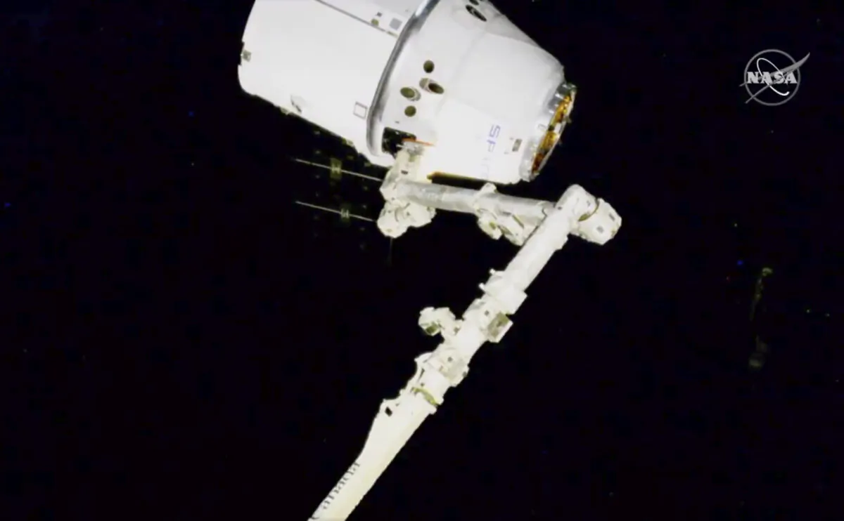 NASA astronauts Andrew Morgan and Jessica Meir use the International Space Station's robot arm to capture the Dragon capsule on March 9, 2020. (NASA via AP)
