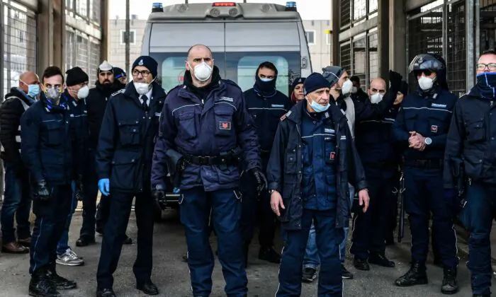 Prison Police officers stand guard after an ambulance (Rear) entered the SantAnna prison during a protest of inmates' relatives in Modena, Emilia-Romagna, in one of Italy's quarantine red zones on March 9, 2020. (Piero Cruciatti/AFP via Getty Images)