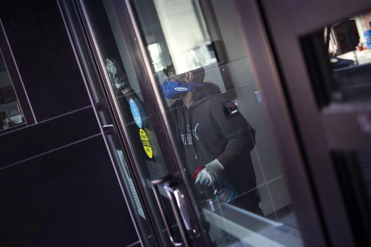A worker disinfects the front doors of the School Without Walls High School, which was closed today after a member of the school's staff reported close contact with a person who tested positive for coronavirus, in Washington on March 9, 2020. (Win McNamee/Getty Images)